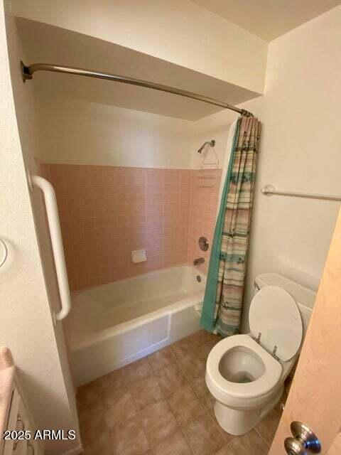 full bath featuring shower / bath combination with curtain, toilet, and tile patterned floors