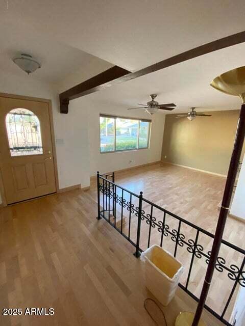 entrance foyer with baseboards, light wood-style flooring, beamed ceiling, and a ceiling fan