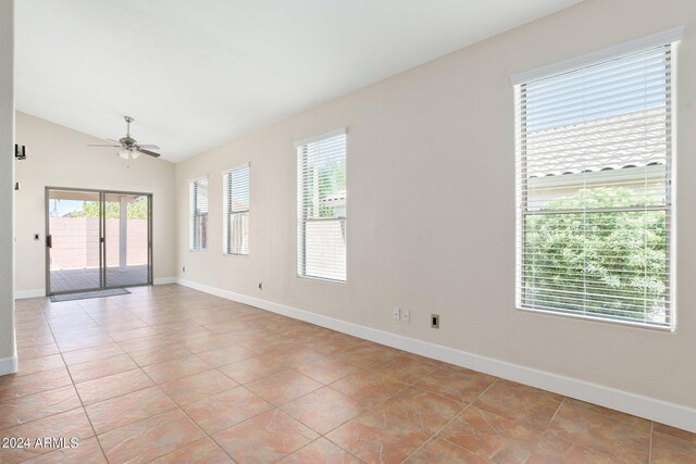 spare room featuring lofted ceiling, light tile patterned flooring, ceiling fan, and plenty of natural light