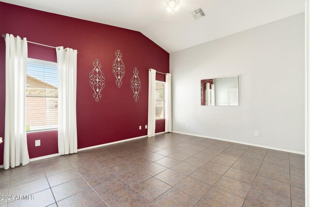 tiled spare room featuring lofted ceiling