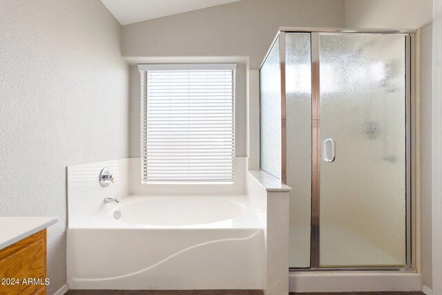 bathroom with independent shower and bath, vanity, lofted ceiling, and a healthy amount of sunlight