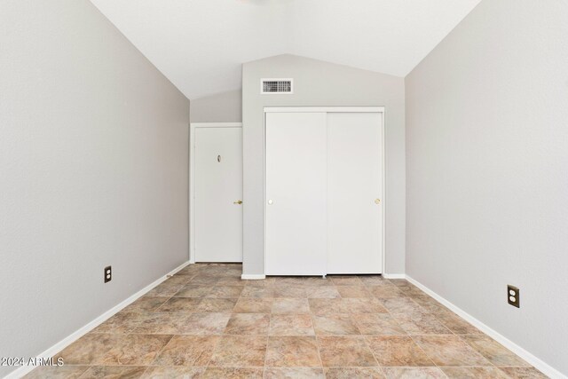 unfurnished bedroom with lofted ceiling and a closet