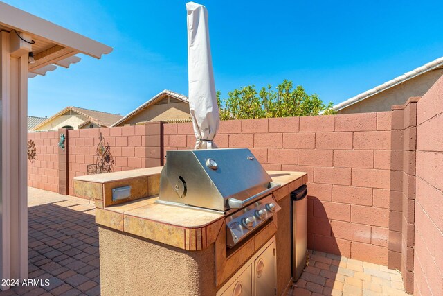 view of patio with area for grilling and a grill