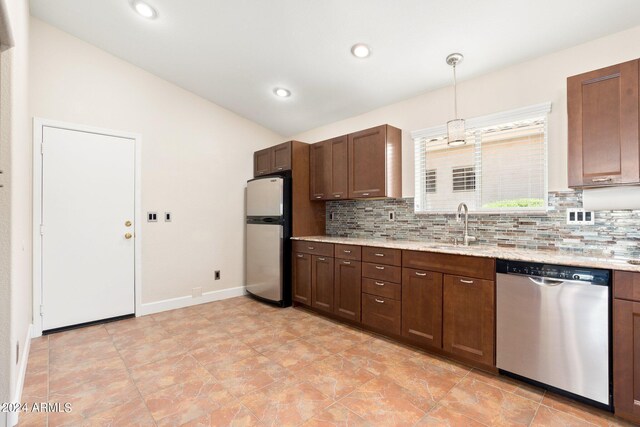 kitchen with appliances with stainless steel finishes, hanging light fixtures, vaulted ceiling, tasteful backsplash, and sink