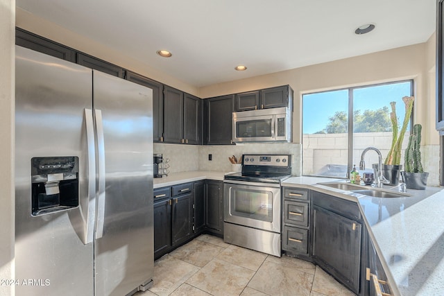 kitchen with backsplash, sink, light stone countertops, and stainless steel appliances