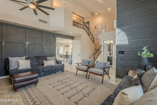 living room featuring ceiling fan with notable chandelier, wood walls, and high vaulted ceiling