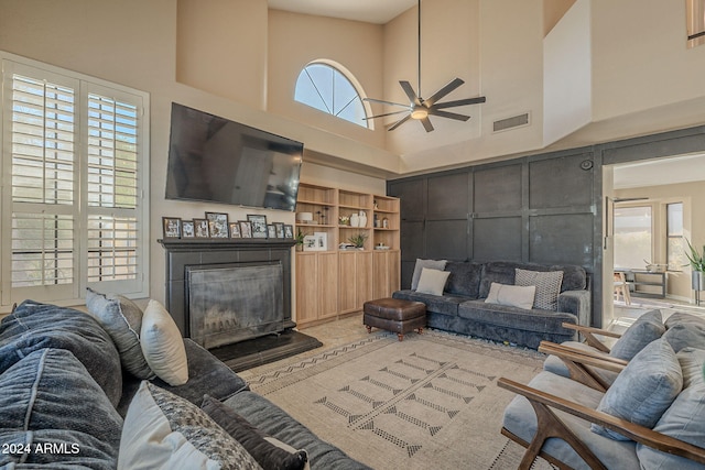 living room featuring ceiling fan, a towering ceiling, and a wealth of natural light