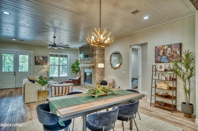 dining room with a fireplace, hardwood / wood-style flooring, ceiling fan with notable chandelier, and wooden ceiling