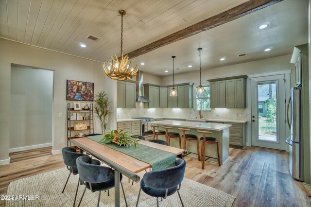 dining space with beamed ceiling, light hardwood / wood-style flooring, and a chandelier