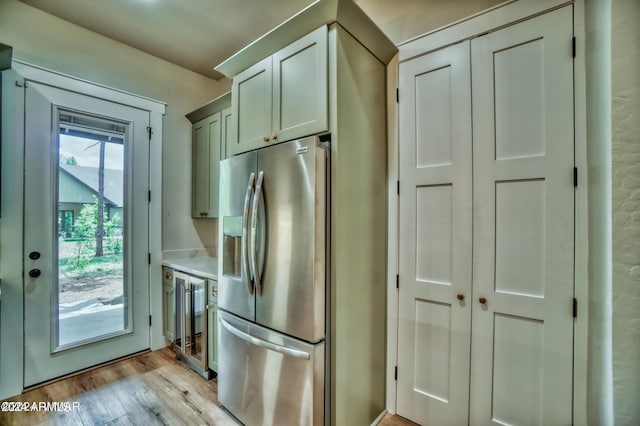 kitchen with light hardwood / wood-style flooring, beverage cooler, and stainless steel fridge with ice dispenser