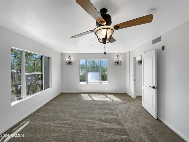 spare room with carpet flooring, ceiling fan, and a wealth of natural light