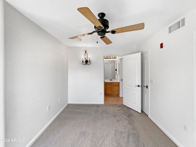 carpeted empty room with ceiling fan with notable chandelier and sink