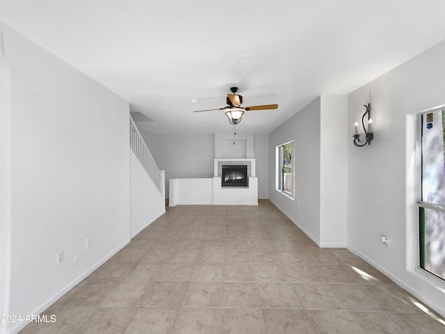 unfurnished living room featuring ceiling fan with notable chandelier