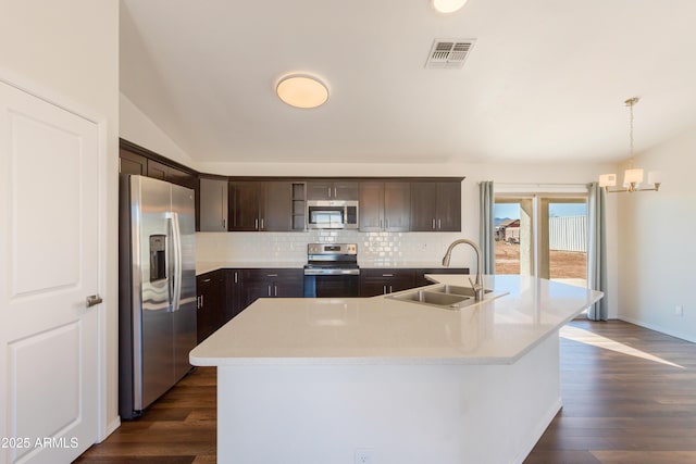 kitchen featuring sink, dark wood-type flooring, stainless steel appliances, a center island with sink, and dark brown cabinetry