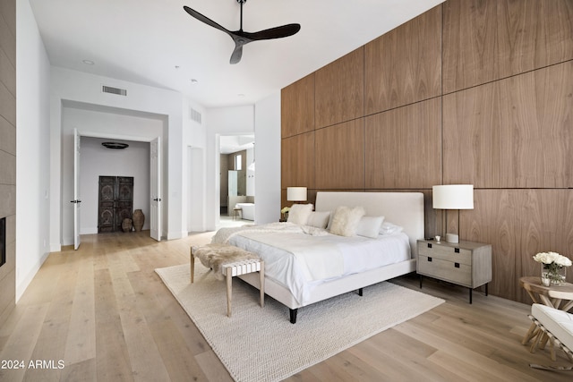 bedroom with visible vents, a fireplace, ensuite bath, and light wood finished floors