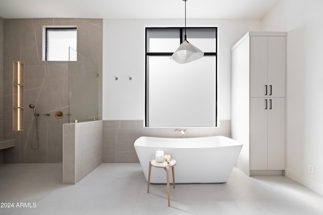 bathroom featuring a freestanding tub, a walk in shower, tile walls, and tile patterned floors