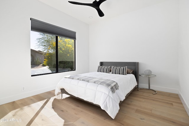 bedroom with ceiling fan, wood finished floors, and baseboards