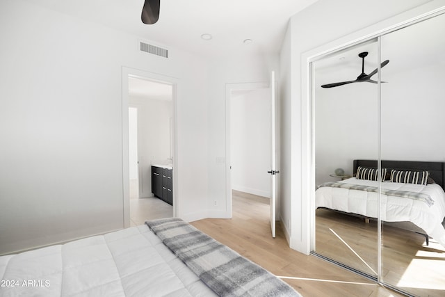 bedroom with light wood-style floors, ceiling fan, visible vents, and a closet