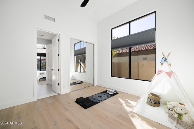 interior space featuring a ceiling fan, visible vents, baseboards, and wood finished floors