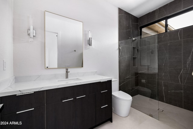 bathroom with tiled shower, vanity, and toilet