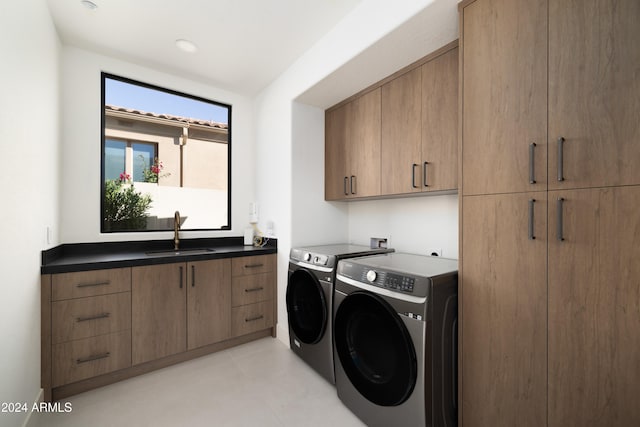 washroom with cabinets, washing machine and dryer, and sink