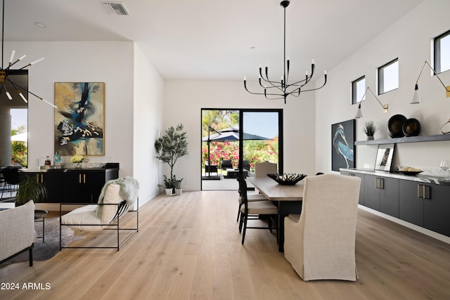 dining room featuring wood-type flooring, a healthy amount of sunlight, and a notable chandelier