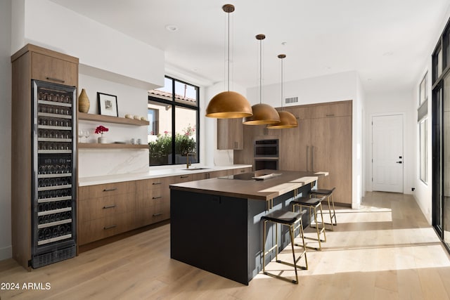 kitchen featuring wine cooler, pendant lighting, light wood finished floors, open shelves, and a sink