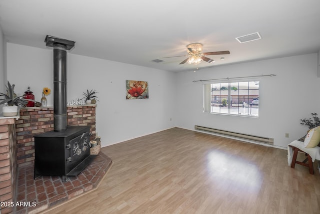 3098 N Starlight Dr, Prescott Valley, AZ 86314 - unfurnished living room featuring a baseboard radiator, a wood stove, a ceiling fan, wood finished floors, and baseboards