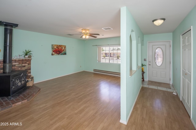 3098 N Starlight Dr, Prescott Valley, AZ 86314 - foyer featuring a baseboard radiator, wood finished floors, a ceiling fan, a wood stove, and baseboards