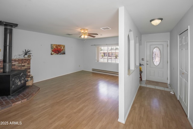 3098 N Starlight Dr, Prescott Valley, AZ 86314 - entryway with a baseboard heating unit, light wood-style floors, ceiling fan, a wood stove, and baseboards