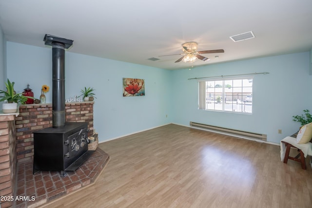 3098 N Starlight Dr, Prescott Valley, AZ 86314 - living area featuring a baseboard radiator, a wood stove, a ceiling fan, wood finished floors, and baseboards