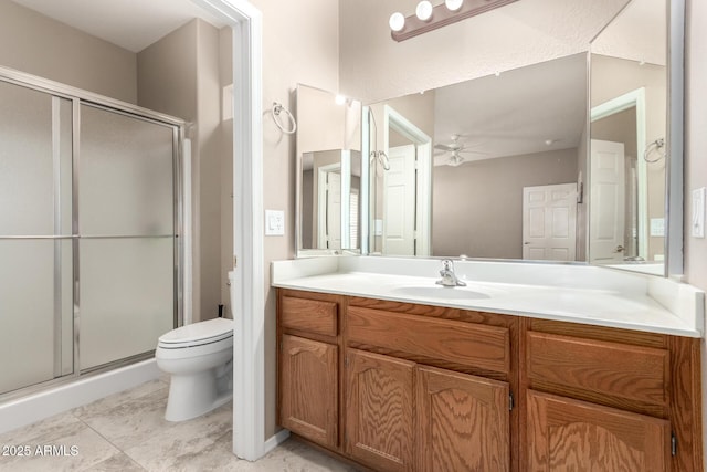 bathroom featuring a shower with door, vanity, ceiling fan, and toilet