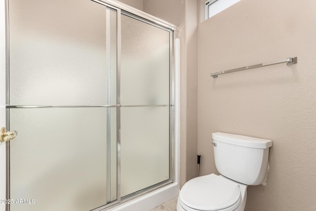 bathroom with toilet and a shower with shower door