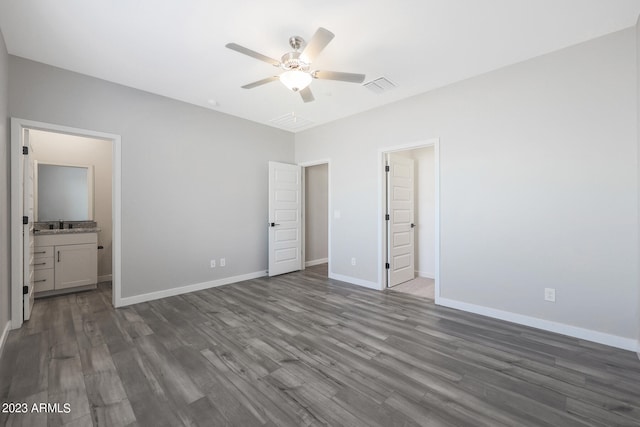 unfurnished bedroom with visible vents, a ceiling fan, ensuite bath, wood finished floors, and baseboards