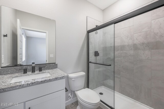 bathroom with vanity, a shower with shower door, and toilet