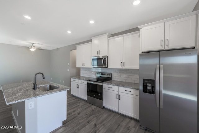 kitchen with stainless steel appliances, a center island with sink, white cabinets, sink, and ceiling fan