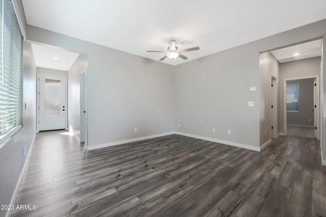 spare room featuring a ceiling fan, visible vents, baseboards, and dark wood-type flooring