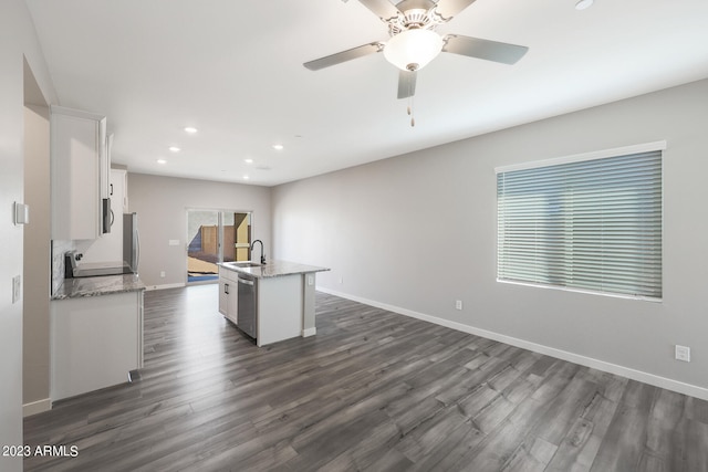 kitchen with dark wood-style floors, a kitchen island with sink, stainless steel appliances, white cabinetry, and a sink