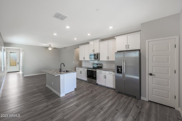 kitchen with appliances with stainless steel finishes, white cabinets, a center island with sink, sink, and dark wood-type flooring