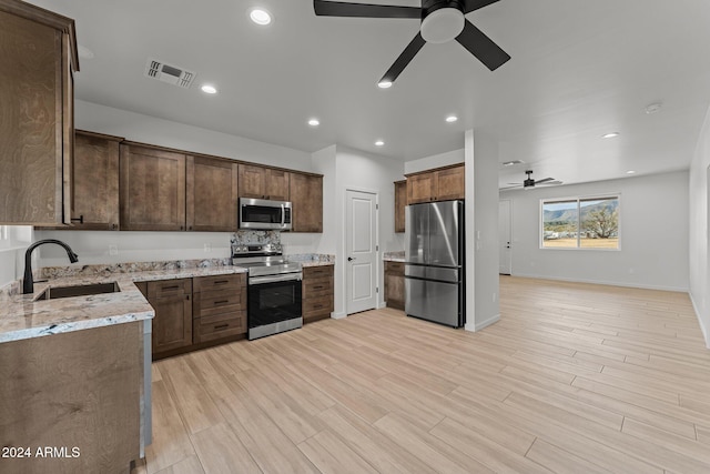 kitchen featuring sink, ceiling fan, light hardwood / wood-style floors, light stone counters, and stainless steel appliances