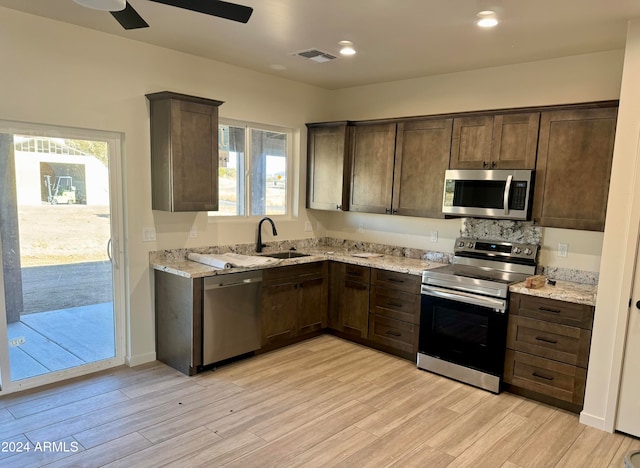 kitchen featuring appliances with stainless steel finishes, light hardwood / wood-style floors, light stone counters, and a healthy amount of sunlight