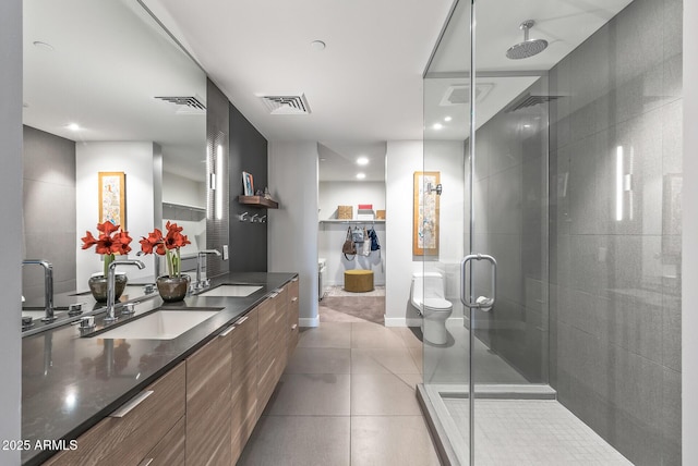 bathroom with a shower with door, vanity, tile patterned floors, and toilet