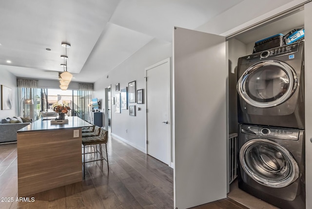 washroom with dark wood-type flooring and stacked washer / dryer