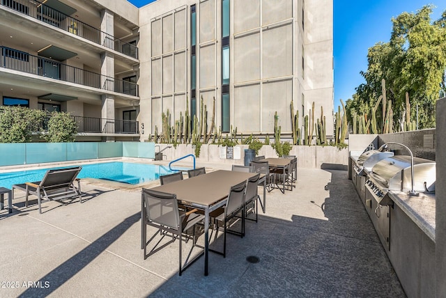 view of pool with exterior kitchen and a patio area