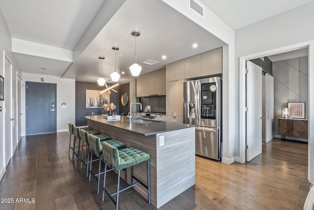 kitchen with pendant lighting, sink, a breakfast bar area, stainless steel fridge, and gray cabinetry