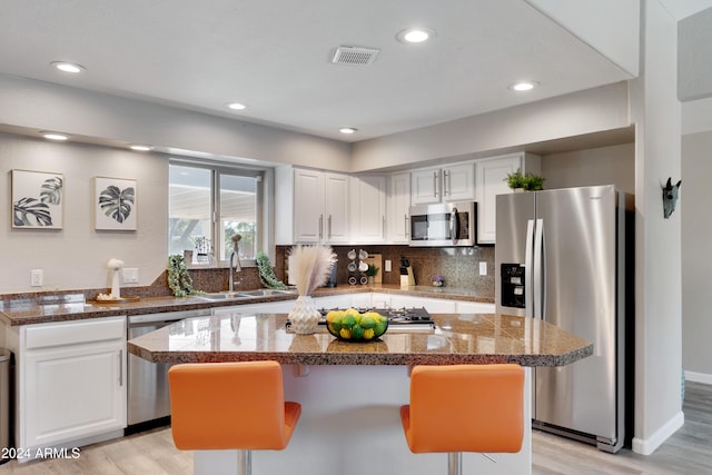 kitchen with light wood-type flooring, a kitchen island, white cabinetry, and stainless steel appliances