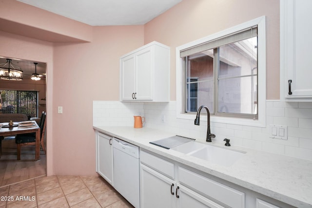 kitchen with light tile patterned flooring, a sink, white cabinetry, light stone countertops, and dishwasher