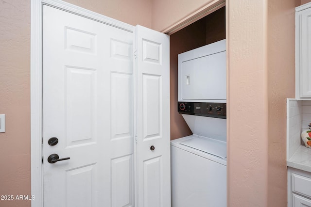 washroom featuring a textured wall, laundry area, and stacked washer / dryer