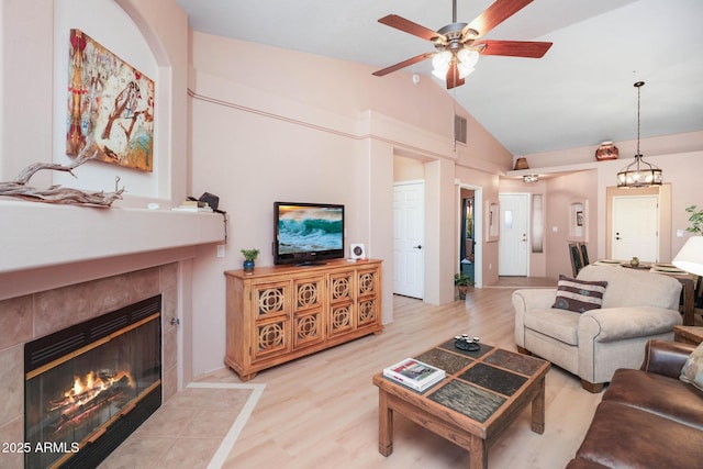 living area with lofted ceiling, ceiling fan, a tile fireplace, wood finished floors, and visible vents