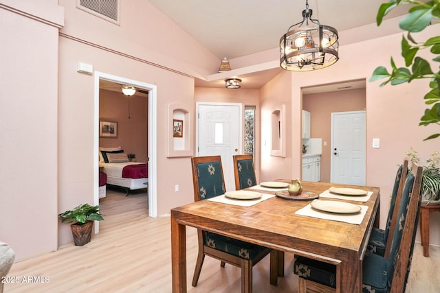 dining area with vaulted ceiling, visible vents, and light wood-style floors